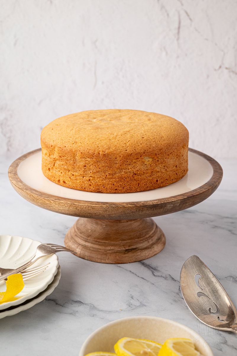 Side view of a traditional Madeira cake on a cake stand with serving utensils nearby.