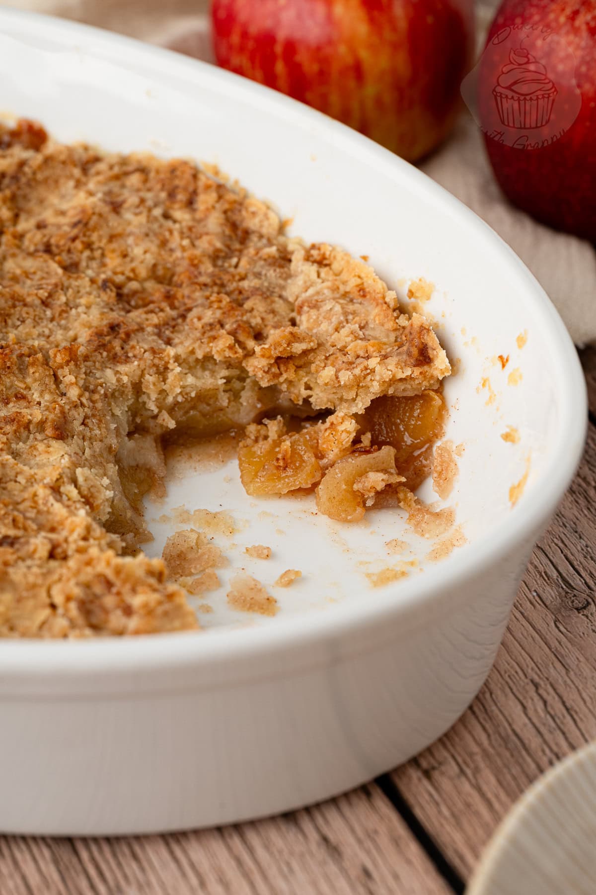 Apple crumble with a portion removed, showing apple pieces beneath the crumble topping.