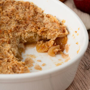 Cross-section of a traditional apple crumble recipe showing tender, cinnamon-spiced baked apples beneath a shortbread-like topping.