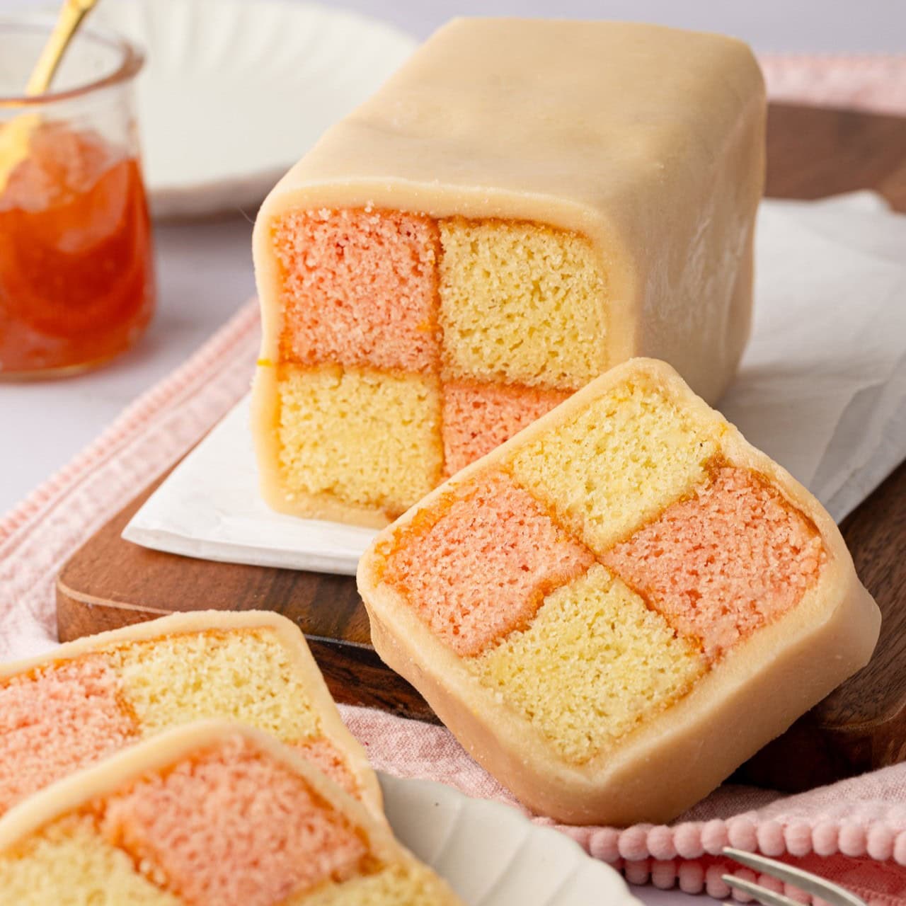 Sliced Battenberg cake, showing the pink and plain checker pattern inside.