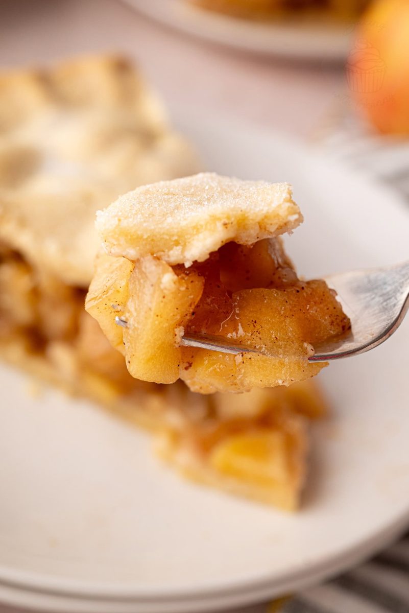 Close-up of a forkful of apple pie, showing tender spiced apple slices and buttery pastry - part of an apple pie UK recipe.