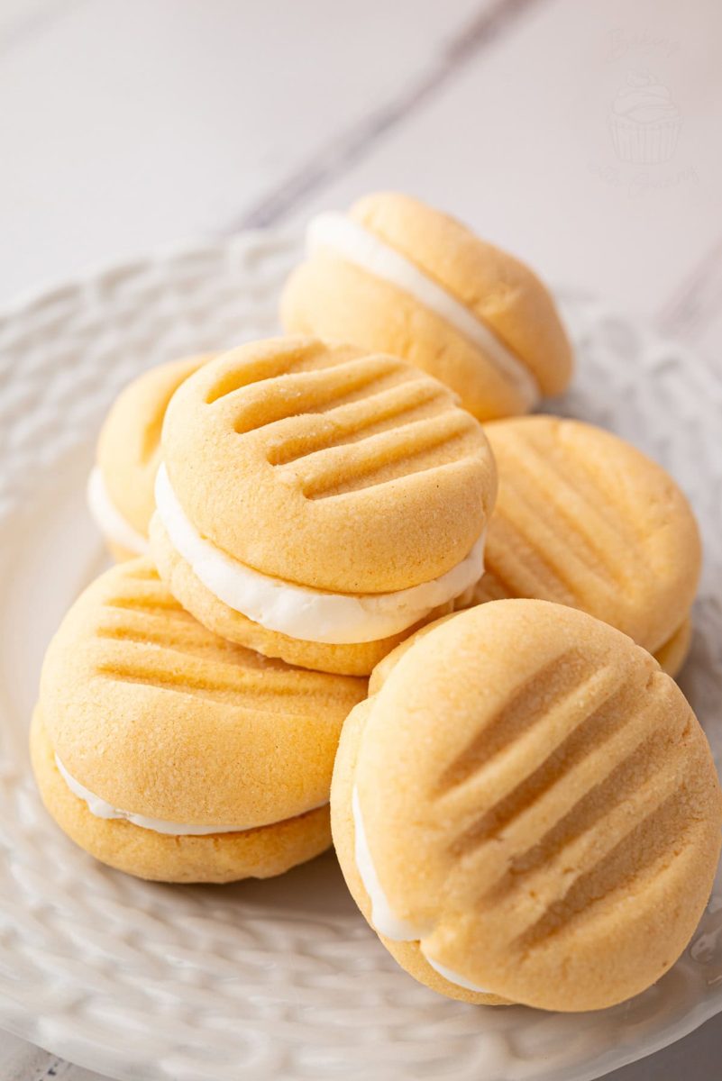 Small plate of custard creams stacked, showing biscuit ridges and creamy filling.