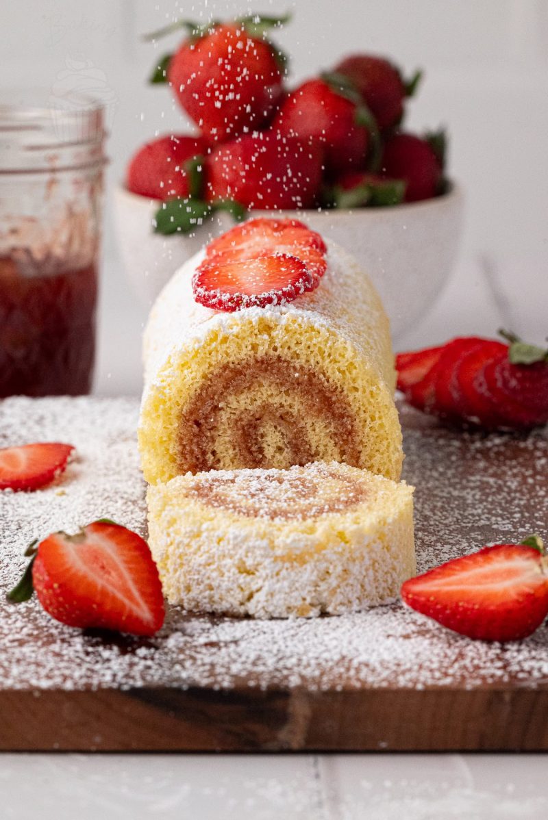 Close-up of a classic British jam Swiss roll cake with strawberry jam filling and a soft sponge spiral.